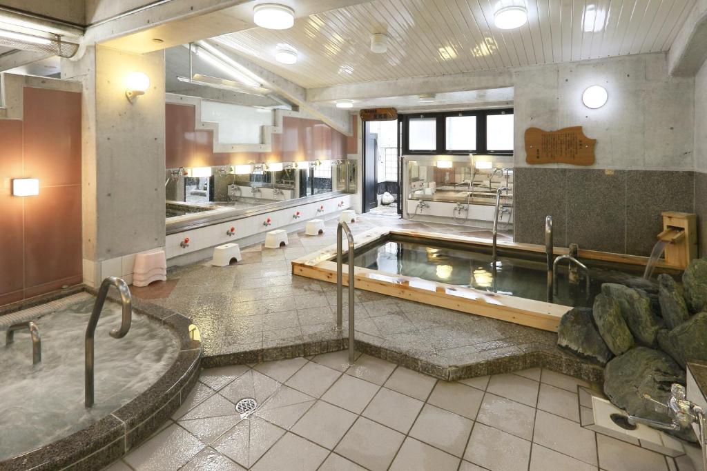 名古屋炭之汤酒店的一间带热水浴缸和浴缸的大浴室