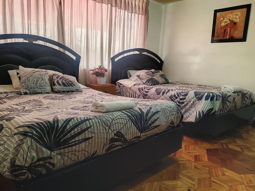 伊瓦拉Hotel Altamira Suites - Ibarra的卧室内两张并排的床