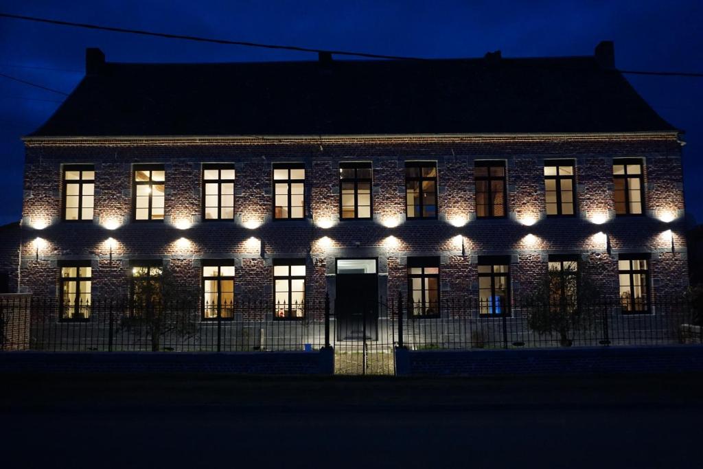 La Ferme Décroué的一座晚上点亮的建筑,灯火通明