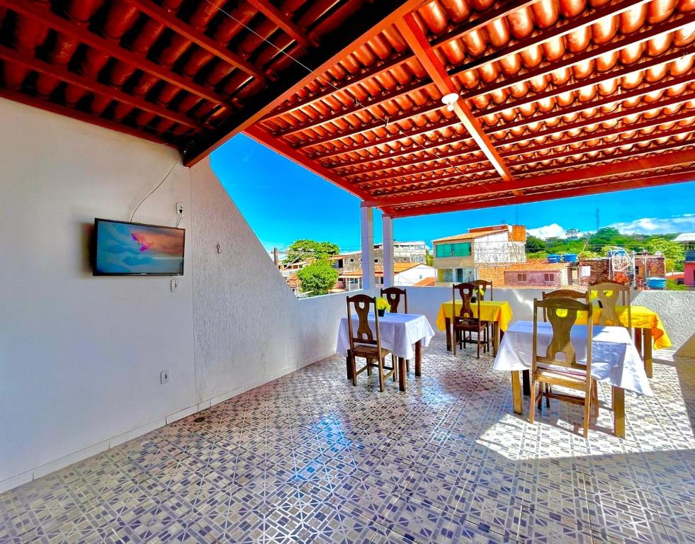 伊塔帕里卡岛维拉克鲁兹Pousada Realce的一个带桌椅的庭院和墙上的电视