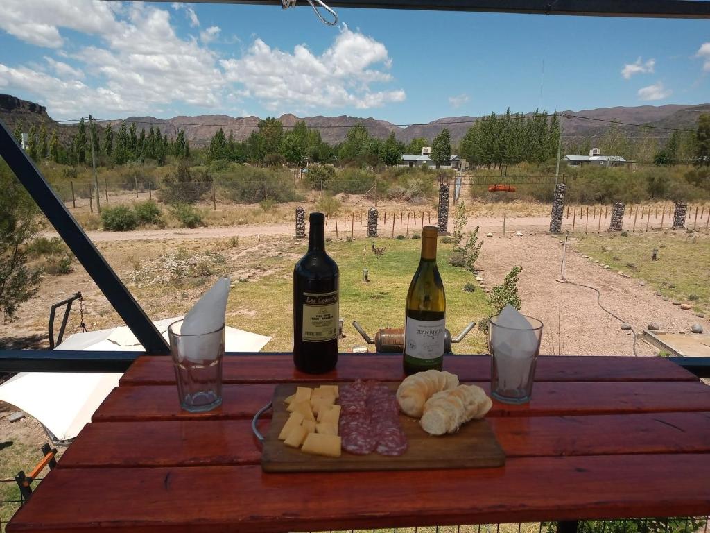 格兰德山谷Balcon al Valle Grande, San Rafael Mendoza的木桌旁的两瓶葡萄酒和奶酪