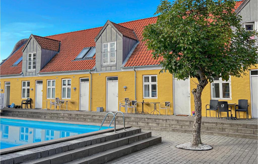 古兹耶姆Kbmandsgrden的黄色的房子,带有游泳池和一棵树