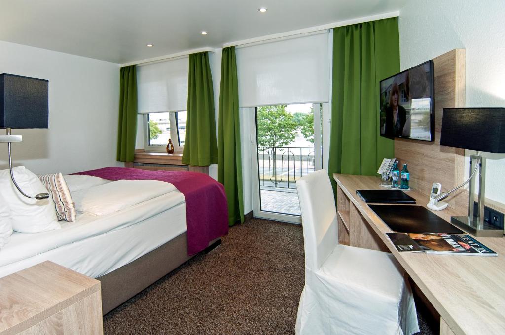 科隆阿列格鲁酒店的酒店客房设有一张床、一张书桌和窗户。