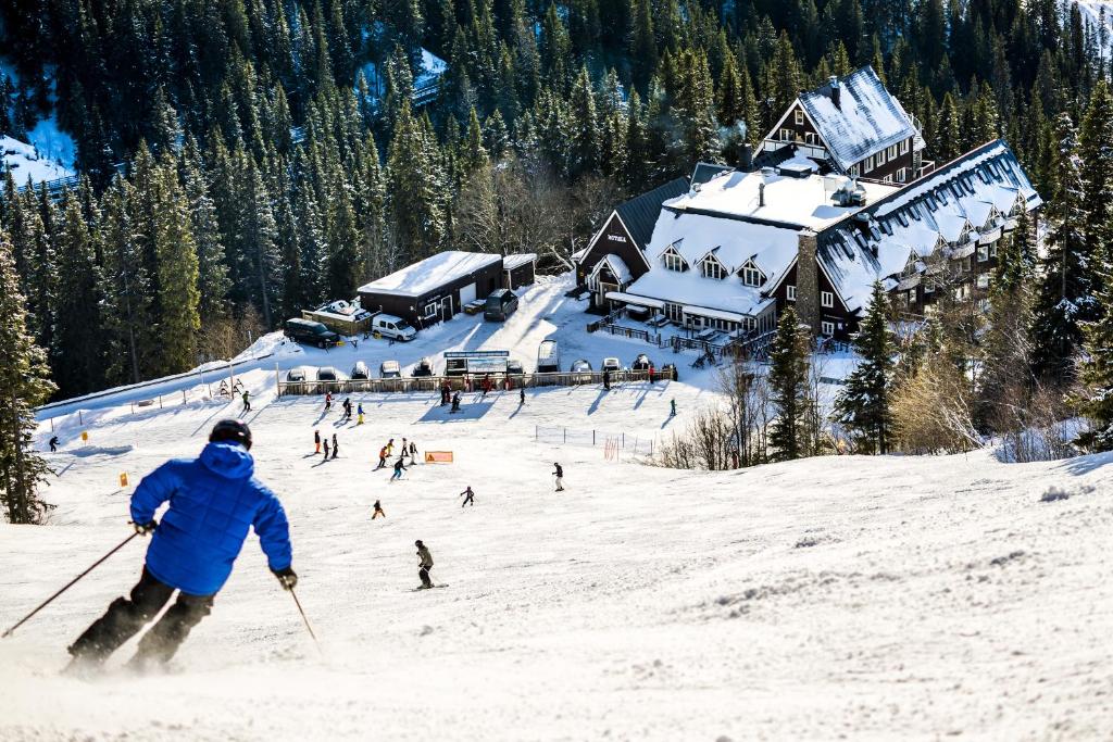 奥勒菲耶加尔登滑雪进出酒店的滑雪者在小屋前的雪覆盖的斜坡上滑雪