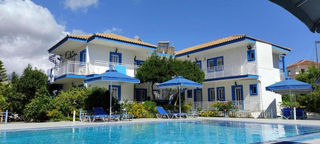 凯法利尼亚岛Blue White Apartments的一座带游泳池和蓝伞的大型建筑