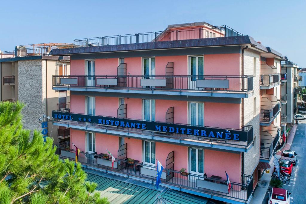 斯波托尔诺米迪泰拉尼酒店的一座高大的粉红色建筑,上面有标志
