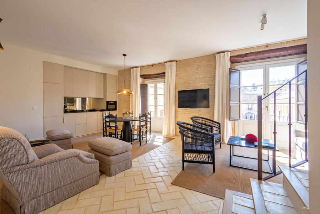 塞维利亚Casa de la Moneda Residences Sevilla的客厅里有一张沙发、一张桌子和几把椅子