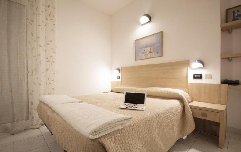 里米尼格罗布斯酒店的一间卧室配有一张带笔记本电脑的床