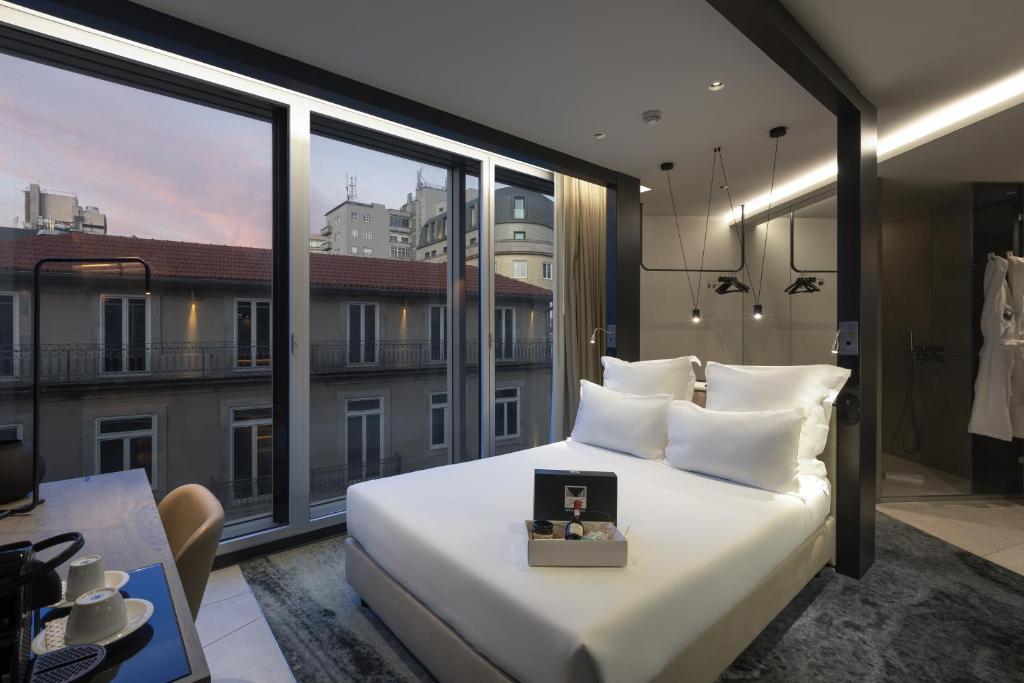 波尔图Porto Royal Bridges Hotel的卧室设有一张白色大床和大窗户