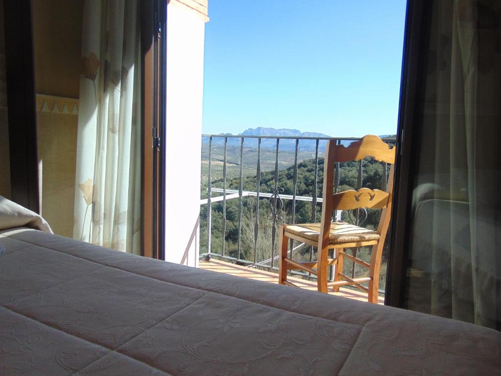 卢塞纳Hotel Sierra de Araceli Lucena的卧室设有1张床和1把椅子,位于阳台