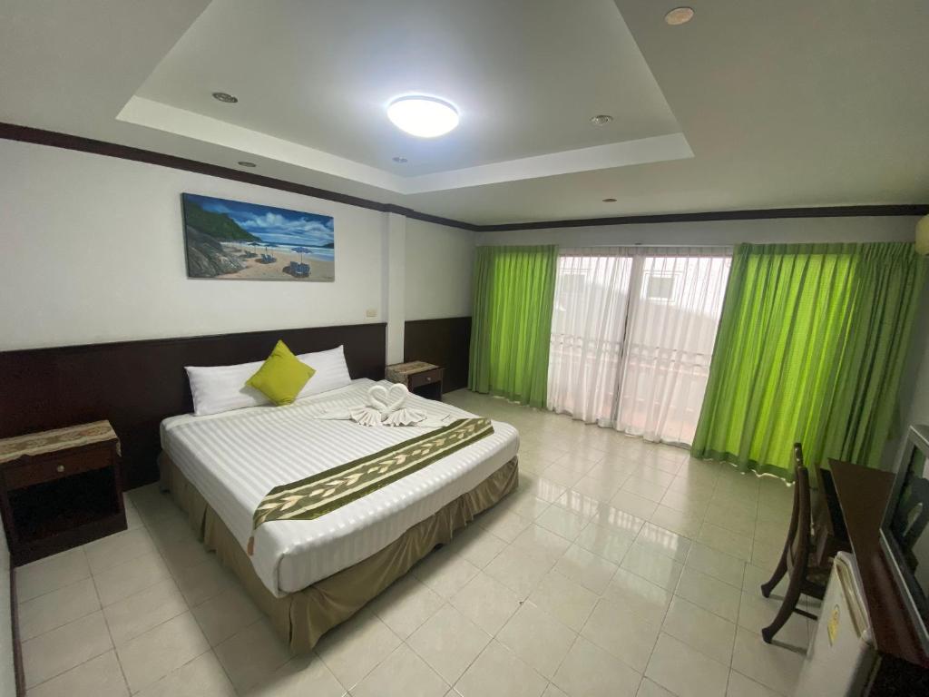 卡塔海滩Sue@Cozy Guesthouse的一间卧室配有一张带绿色窗帘的大床