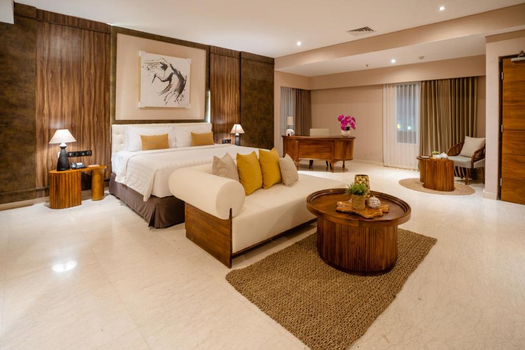 库塔Crystalkuta Hotel - Bali的一间卧室配有一张床、一张沙发和一张桌子