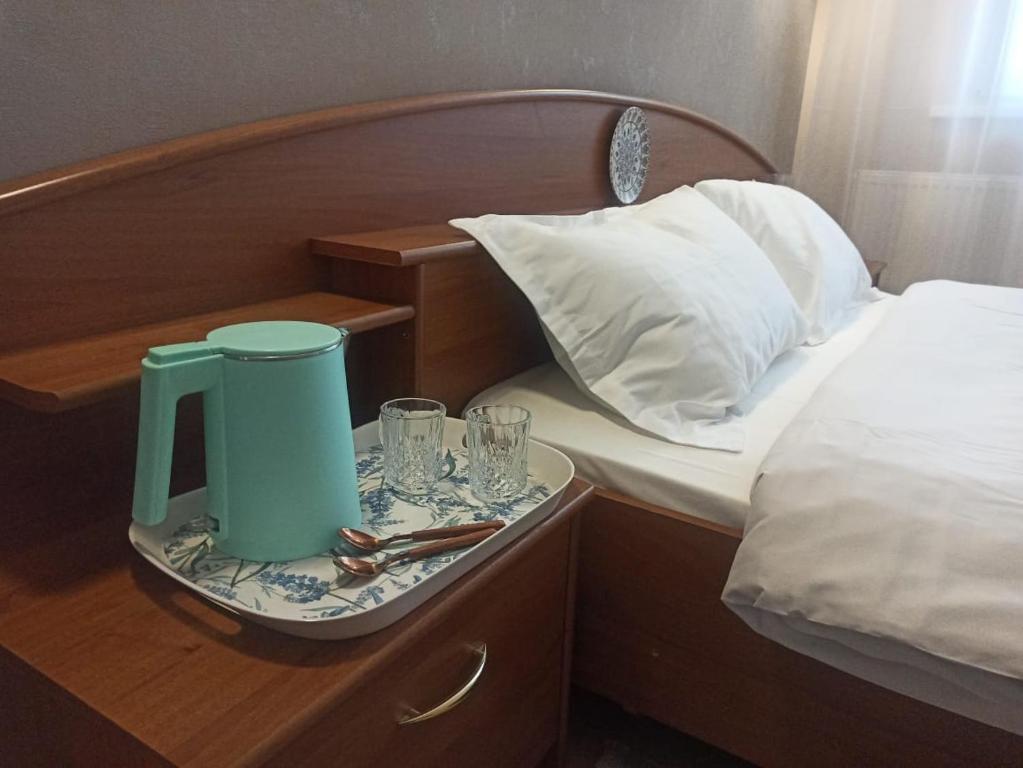 阿斯塔纳1-ком.квартира от ИП Дома света, перекресток Кенесары-Кумисбекова的床上的托盘,包括茶壶和玻璃杯