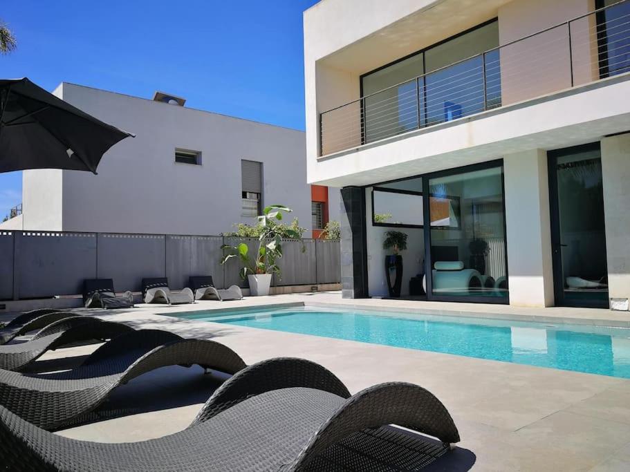 马略卡岛帕尔马Precioso chalet vanguardista的一座房子,设有游泳池、椅子和遮阳伞