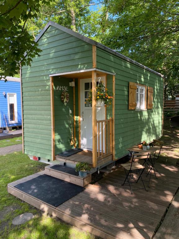 哈姆Tiny House Ahse im PIER9 Tiny House Hotel的绿色的房子,设有门和桌椅