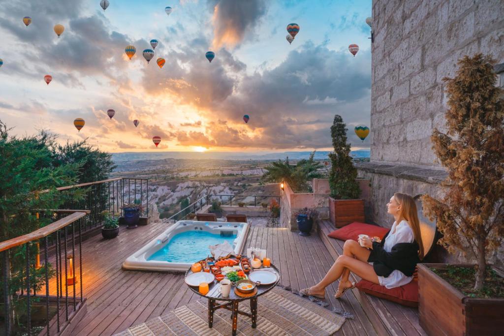 乌奇希萨尔塔斯克纳克拉酒店的坐在天井上观看热气球的女人