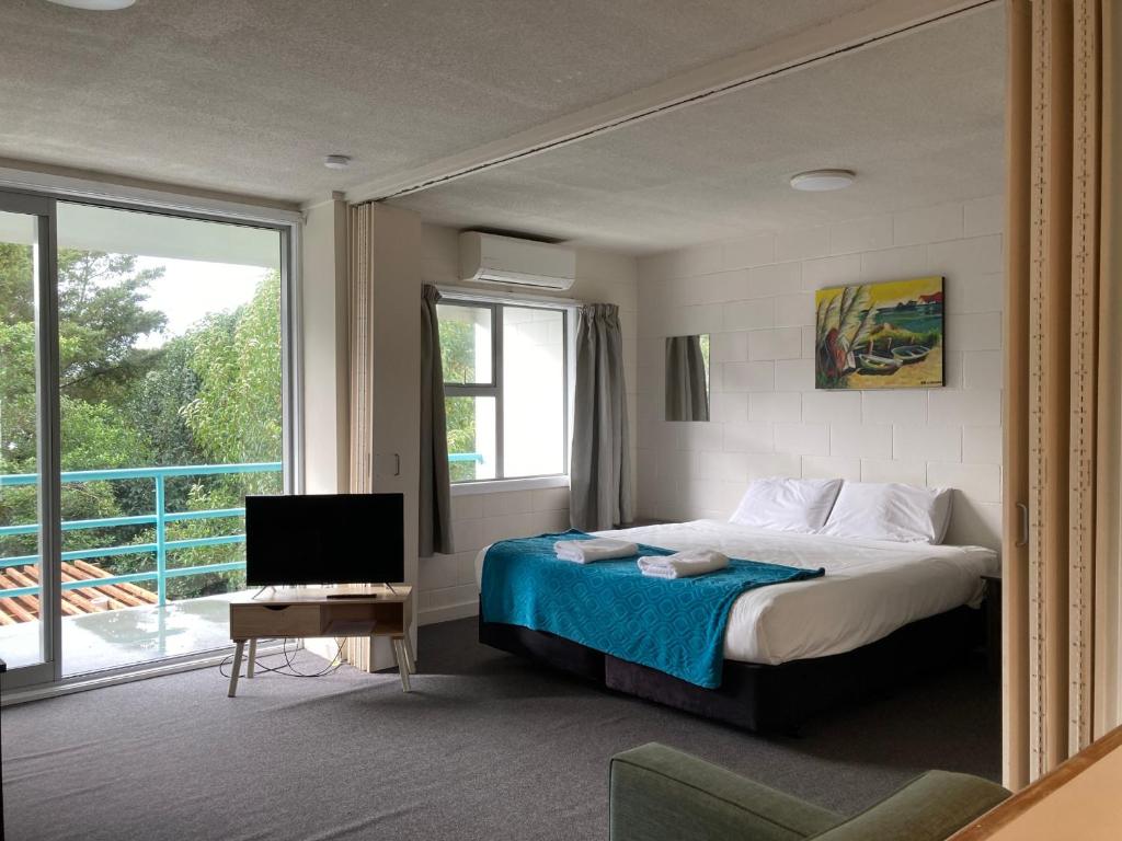 奥克兰City Towers Apartments的一间卧室配有一张床、一台电视和一个阳台