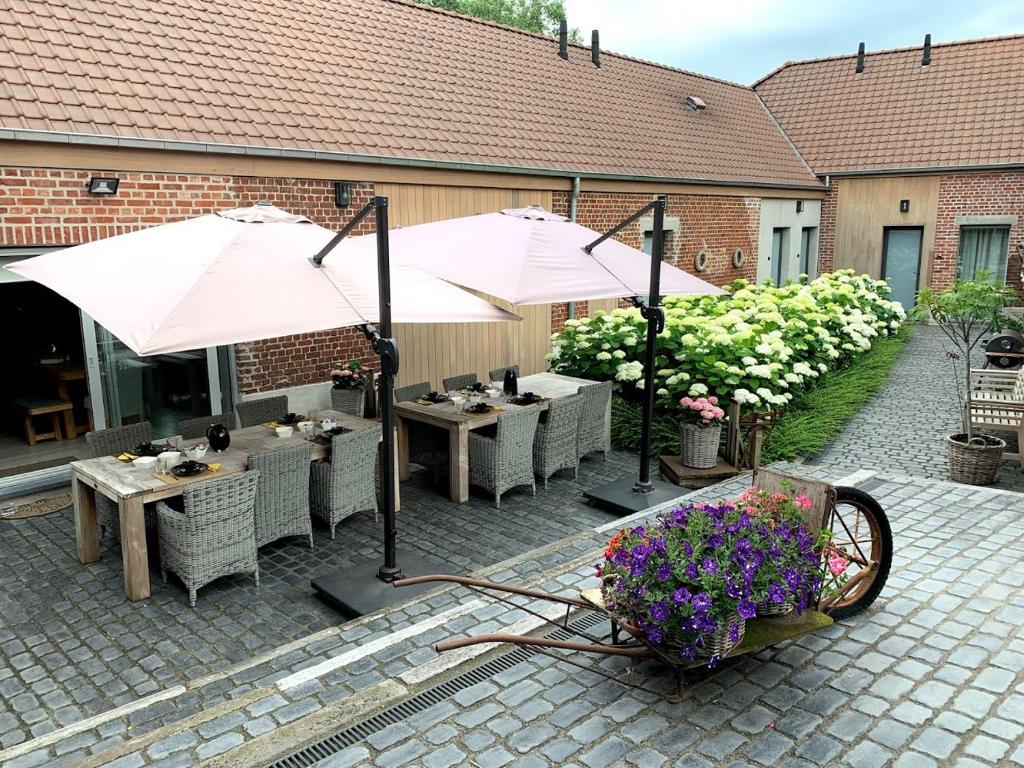 奥德纳尔德B&B 't Oezent的户外庭院配有桌子、遮阳伞和鲜花。
