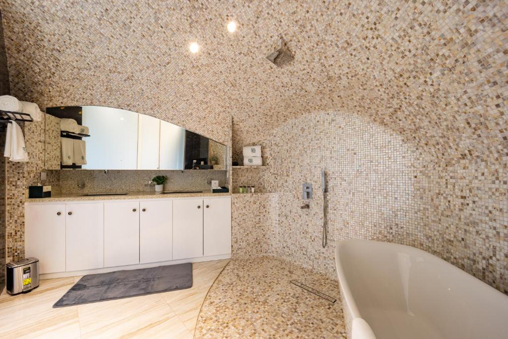拉斯阿尔卡麦Nirvana Retreat的带浴缸和瓷砖墙的浴室