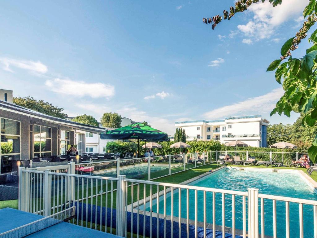 安锡安纳西南部美居酒店的度假村的游泳池,配有椅子和遮阳伞