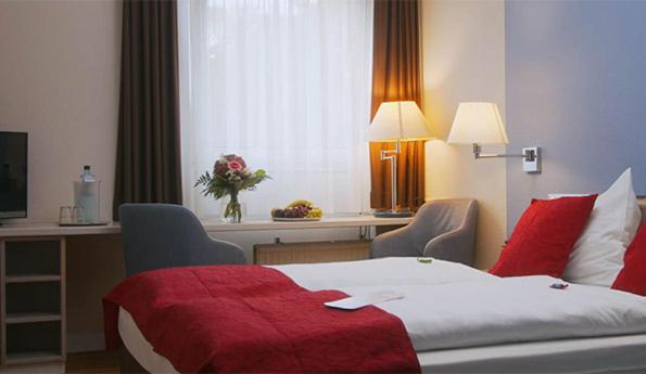 德累斯顿德累斯顿诺瓦利斯酒店的酒店客房,配有一张带红色毯子的床
