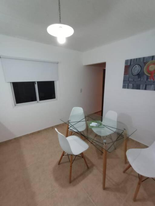 蒙特埃莫索Departamento para dos personas en Monte Hermoso.的一间设有玻璃桌和两把白色椅子的房间