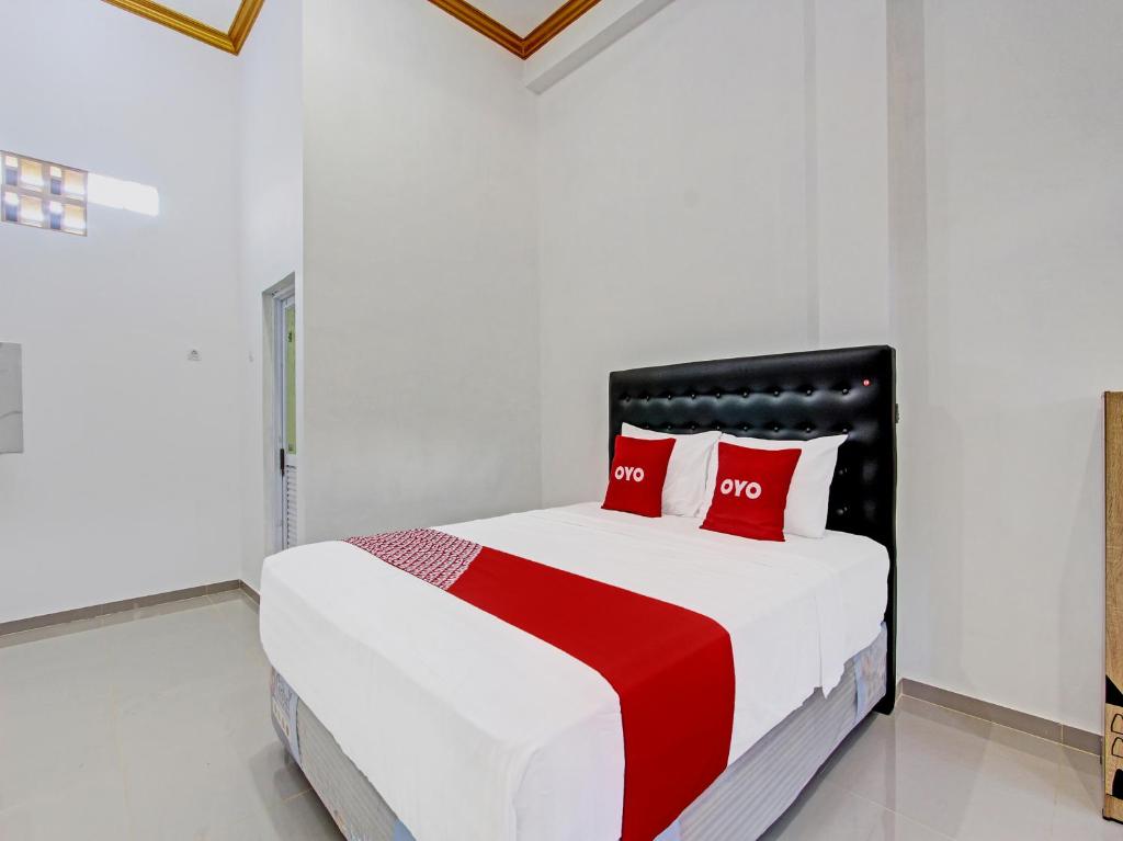日惹Super OYO 92101 Elma Guesthouse的白色卧室配有红色枕头的床
