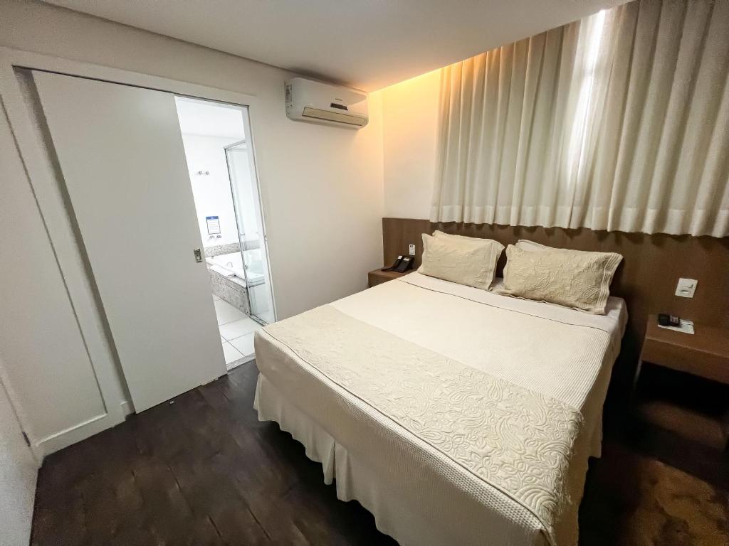 贝洛奥里藏特Nobile Hotel Belo Horizonte的卧室配有白色的床和滑动玻璃门