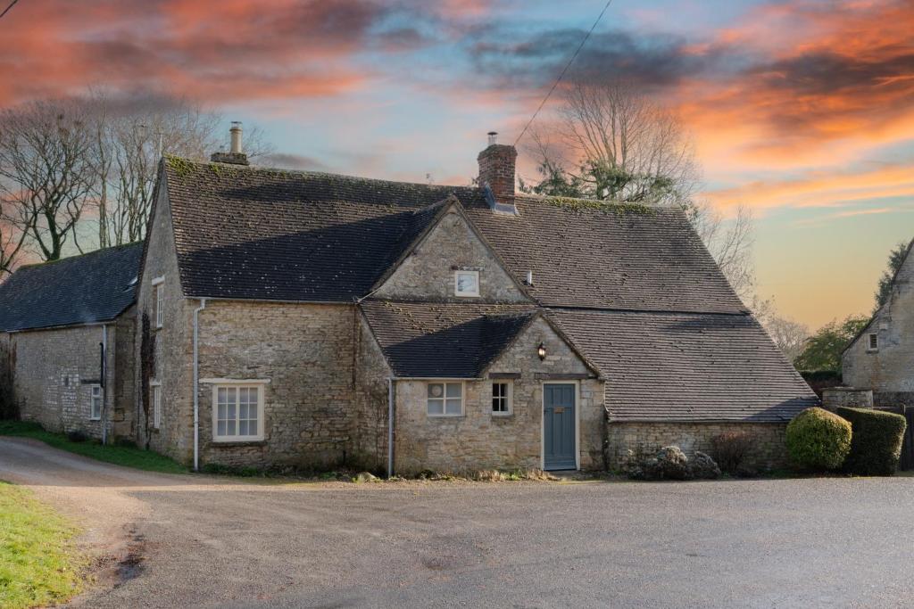 赛伦塞斯特Woodmancote Manor Cottage的街上有屋顶的古老石屋