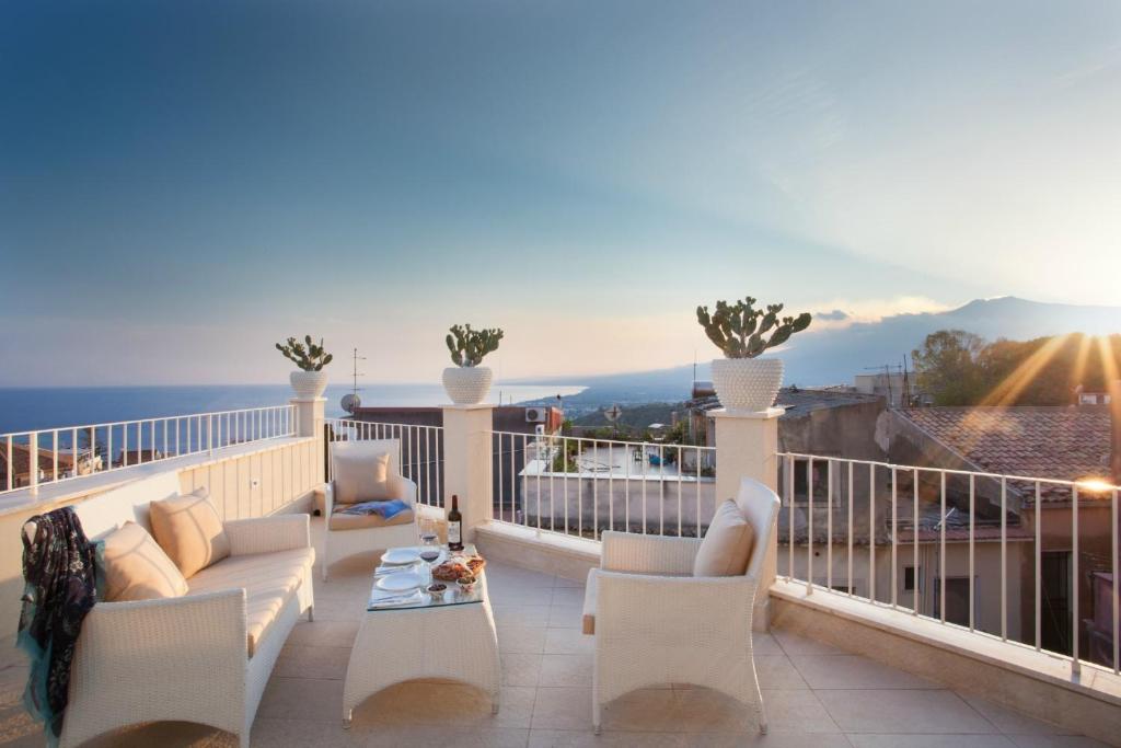 陶尔米纳La Malandrina - Apartments & Suites的阳台配有白色家具,享有海景。