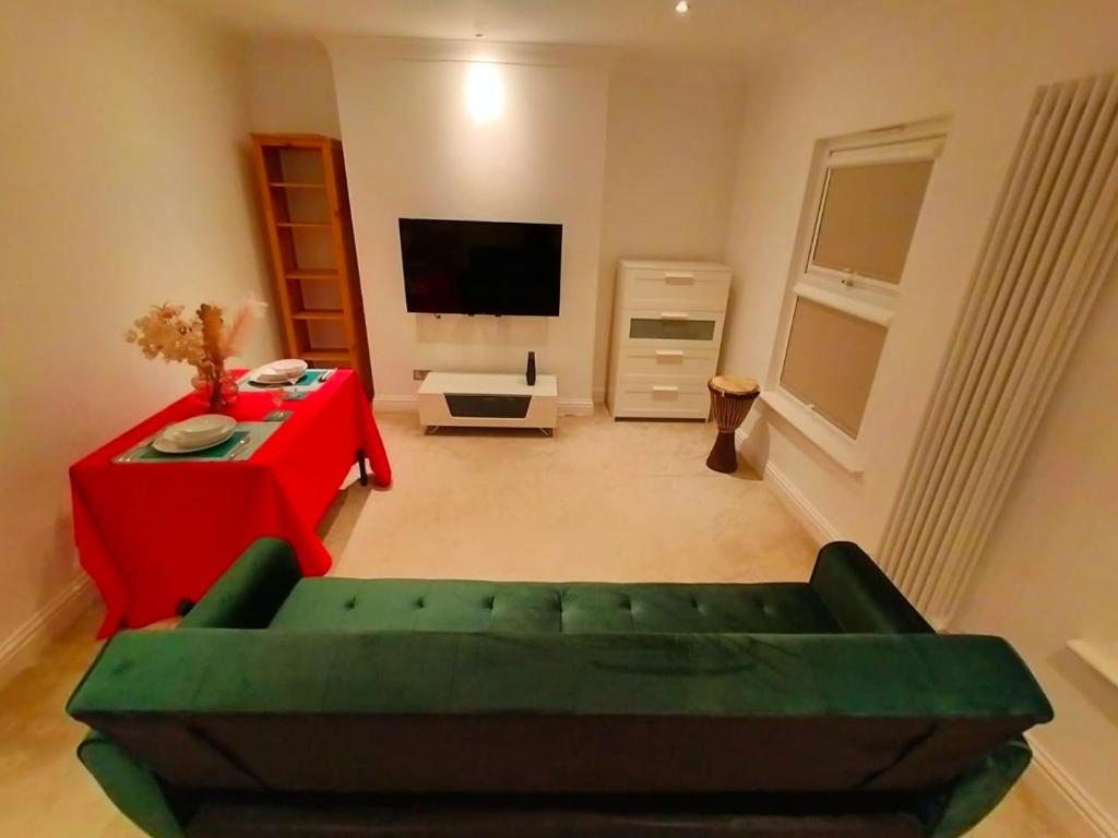 伦敦Fully-equipped flat in the city of London.的客厅配有绿色沙发和红色桌子
