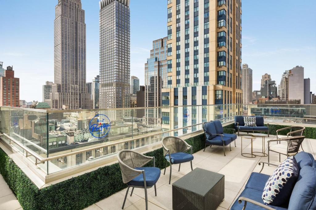 纽约Hyatt Centric Midtown 5th Avenue New York的一个带桌椅的屋顶露台,享有城市美景