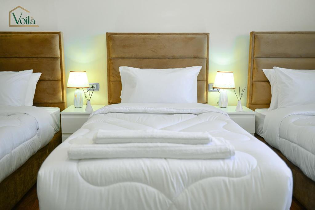 瓦迪穆萨Petra Voila的一间卧室配有两张带白色床单和两盏灯的床。