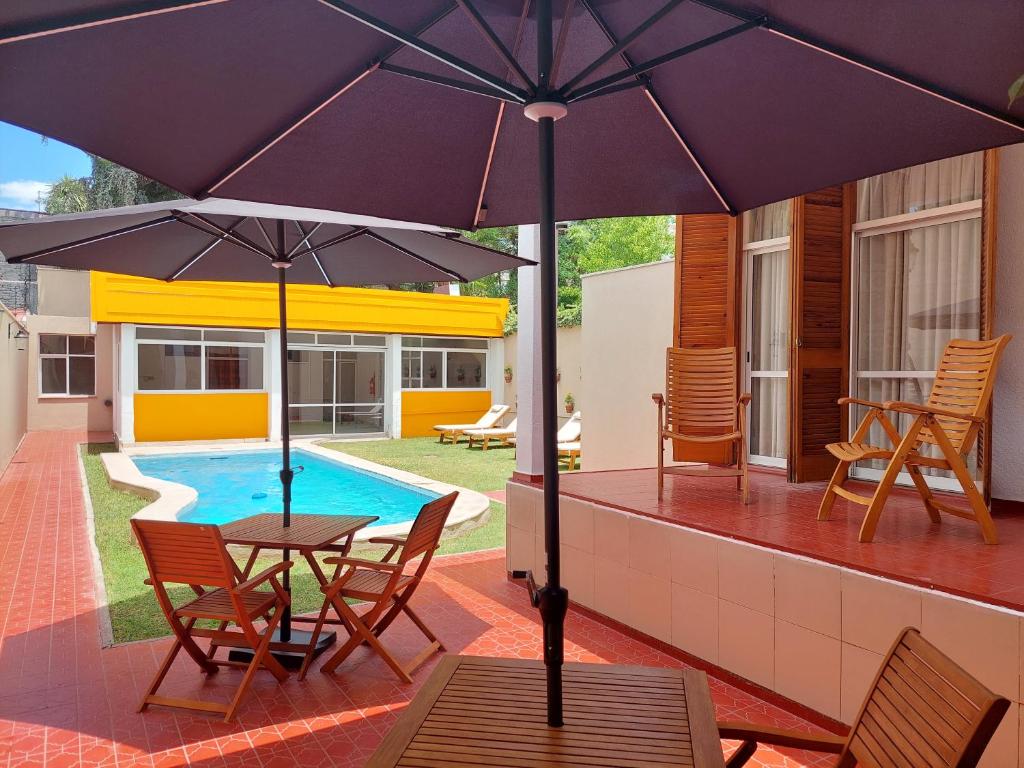门多萨La Casa del Parque B&B的庭院配有桌椅和遮阳伞。