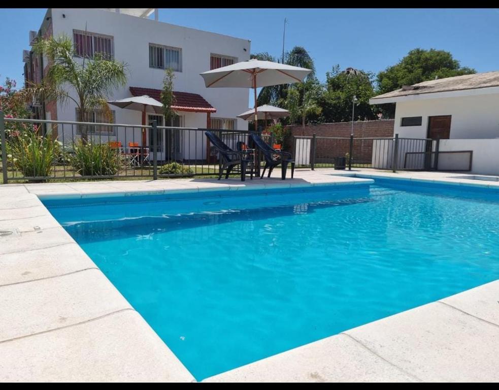 维拉卡洛斯帕兹Posada de Los Lirios的一个带桌子和遮阳伞的蓝色游泳池