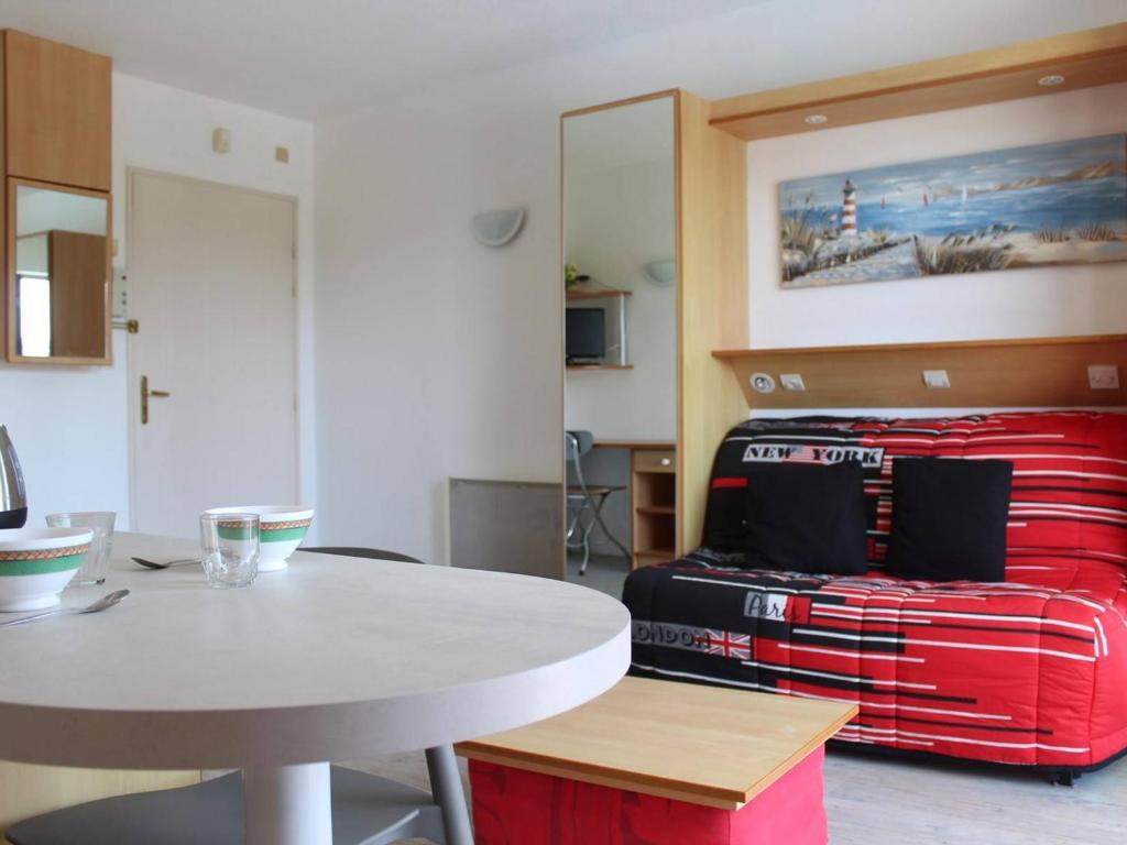 拉罗谢尔Appartement La Rochelle, 1 pièce, 2 personnes - FR-1-246-137的一间房间,配有桌子和一张带红色手提箱的床