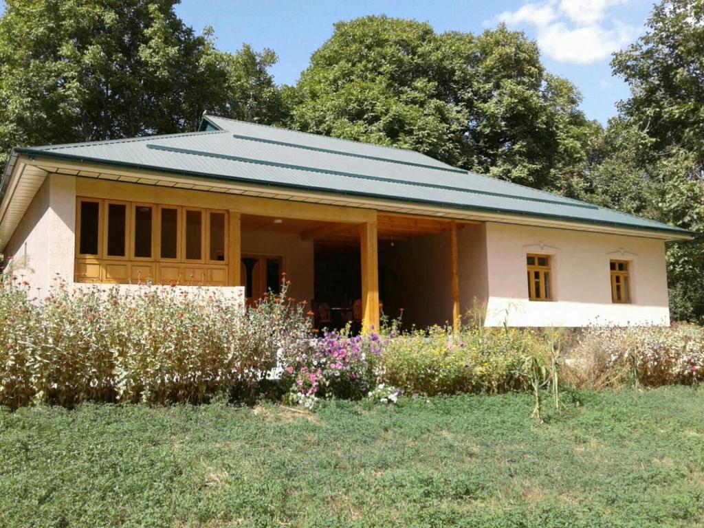 Yukary-UkhumHayat Guesthouse Nuratau Mountains的一座白色的小房子,设有绿色屋顶