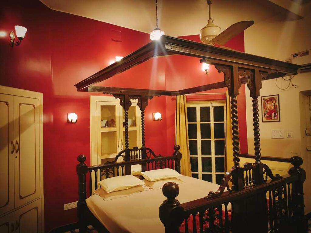 加尔各答OH Kolkata - Sutanuti Homestay的一间红色客房内的卧室,配有一张天蓬床