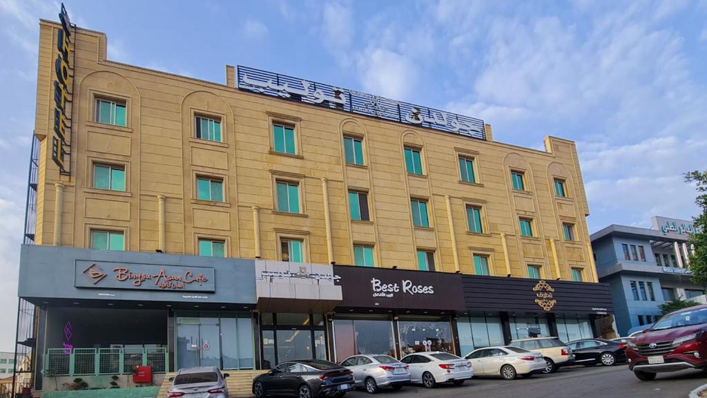 艾卜哈فندق جولدن توليب أبها - GOLDEN TULIP ABHA HOTEl的一座黄色的大建筑,前面有汽车停放