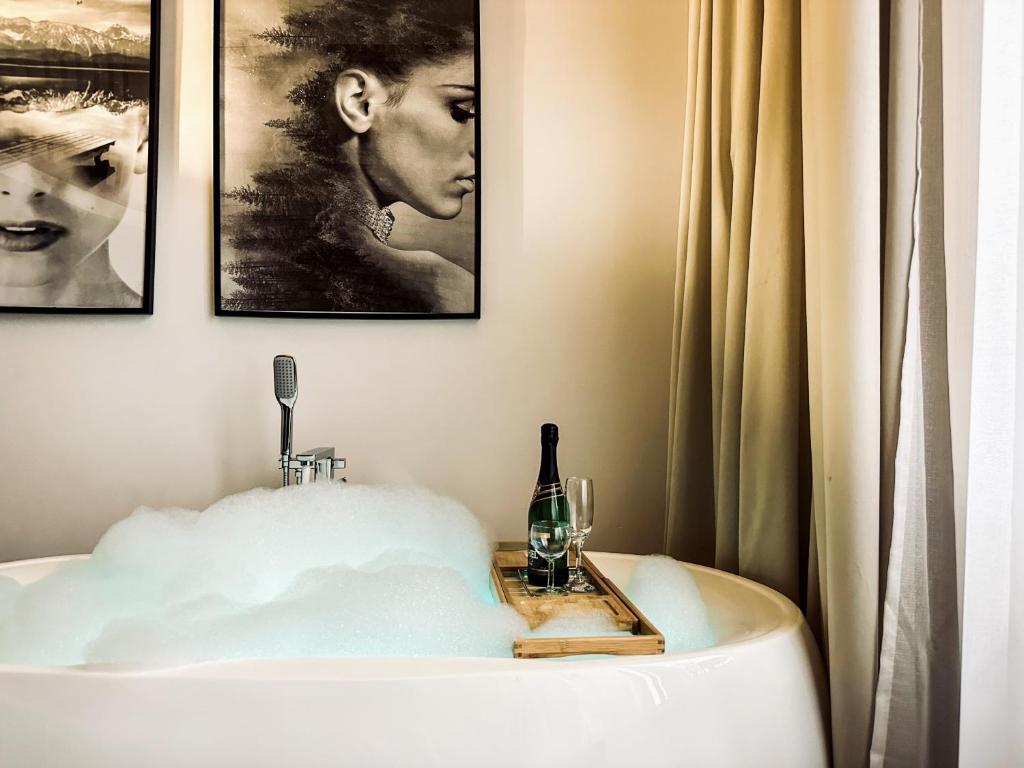 克拉科夫Apartment Premium Jacuzzi for couples, Old Town的浴缸配有一瓶葡萄酒和玻璃