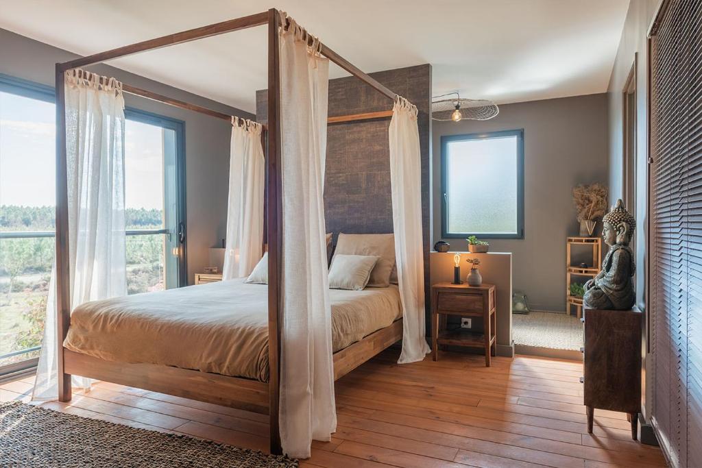 Onesse-et-LaharieLa Grange du Coulin的一间卧室配有一张带窗帘的四柱床