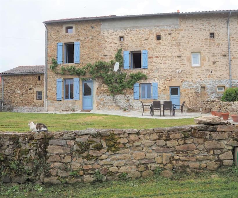 ChâteauponsacTwo Hoots - farmhouse with summer pool.的一只猫坐在一座建筑前的石墙上