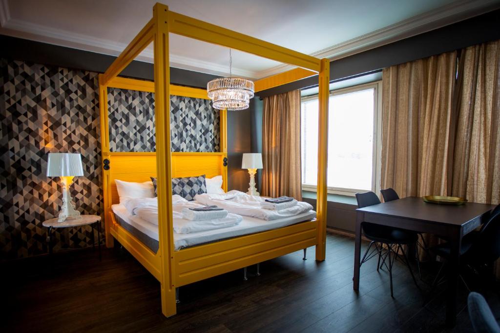 托尔尼奥奥洛夫酒店的一间卧室配有黄色天蓬床和一张书桌