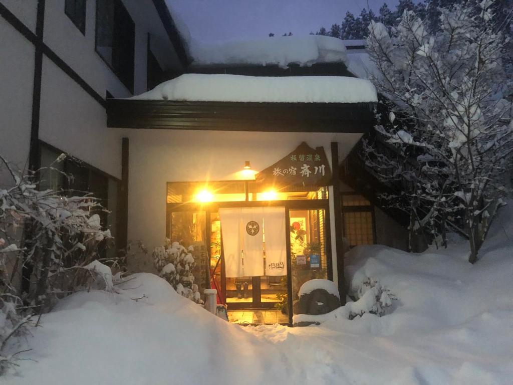 KuroishiTabinoyado Saikawa的门上灯笼罩在雪中的房子