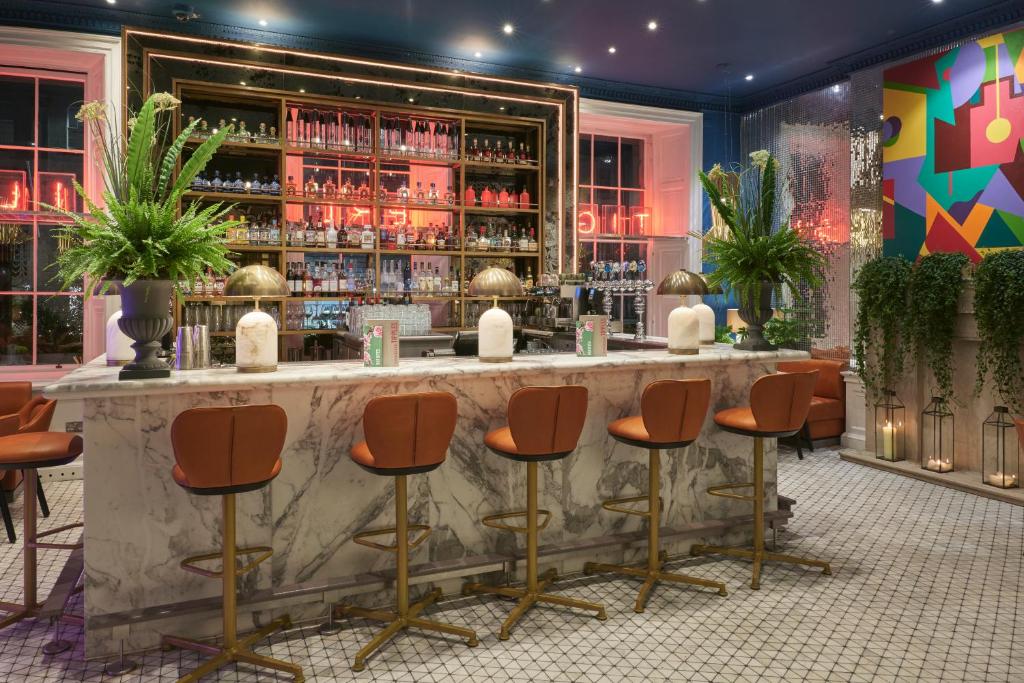 爱丁堡虎皮百合酒店的一间酒吧,在房间内摆放着橙色的酒吧凳子