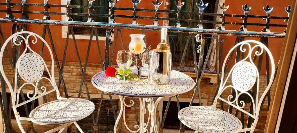 威尼斯My Rialto Palace的桌子、两把椅子和一瓶酒及眼镜