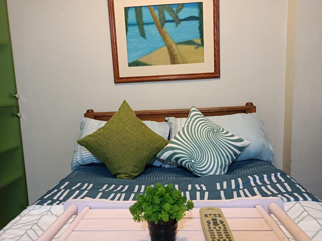 马尼拉WestParc Cedar Alabang的一张带枕头的床和一张带植物的桌子