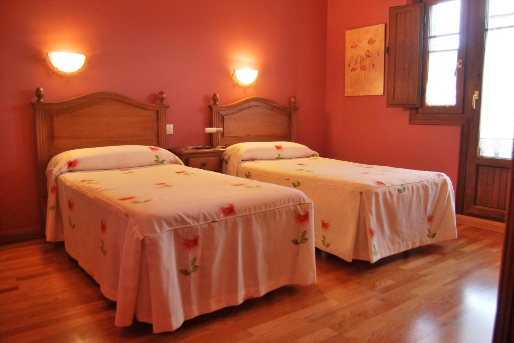 洛斯科拉莱斯-德布埃尔纳贝卡达布尔纳乡村民宿的配有红色墙壁和木地板的客房内的两张床