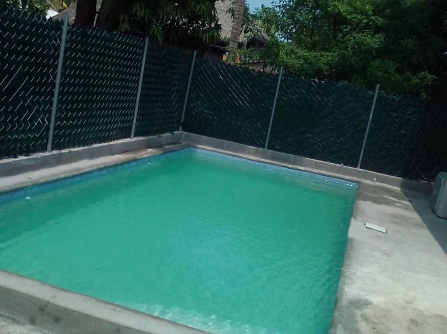 IztapaEl Chalet del Canche的围栏前的绿色水游泳池