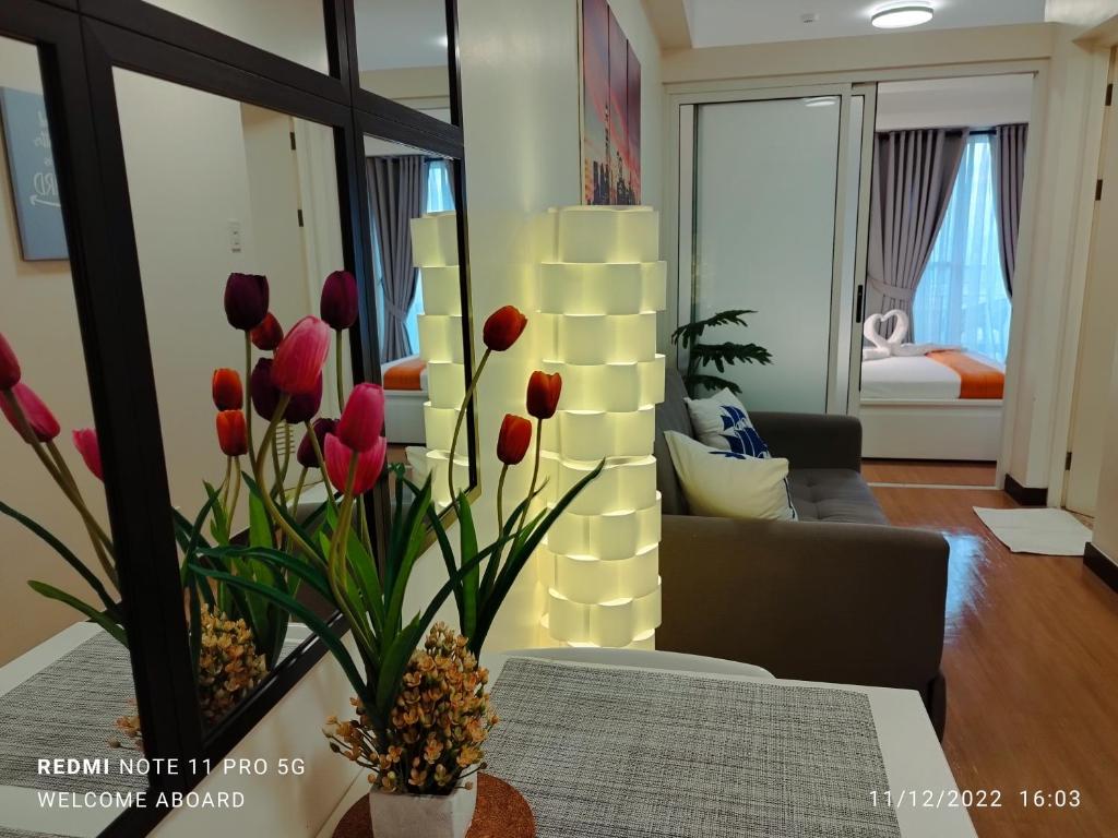 马尼拉Celandine Residence by DMCI的客厅,在桌子上的花瓶里放着红色郁金香